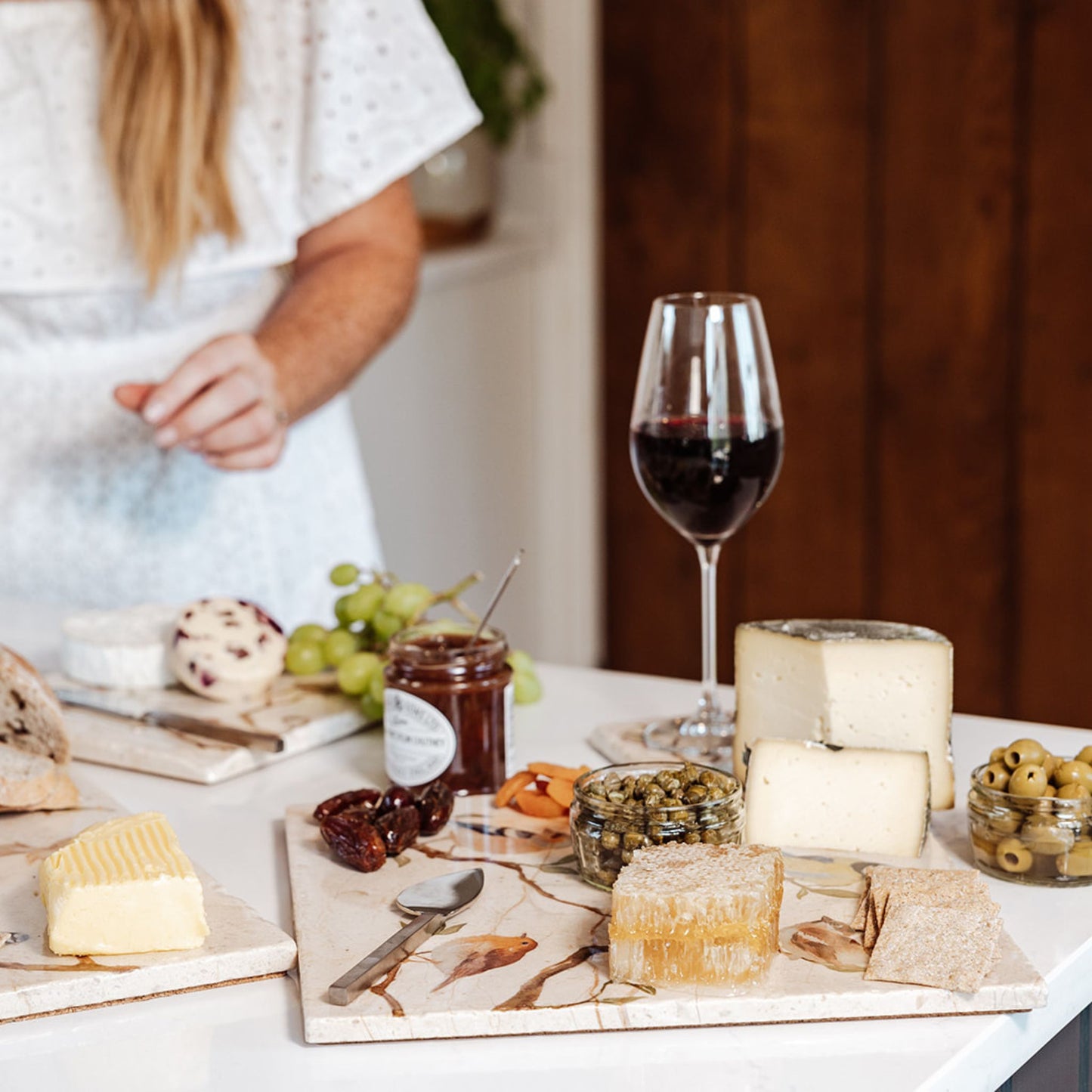 A large marble serving platter with a watercolour design featuring British garden birds on branches. The platter is being used as a cheeseboard, with cheese, crackers, honeycomb and chutney arranged on it.