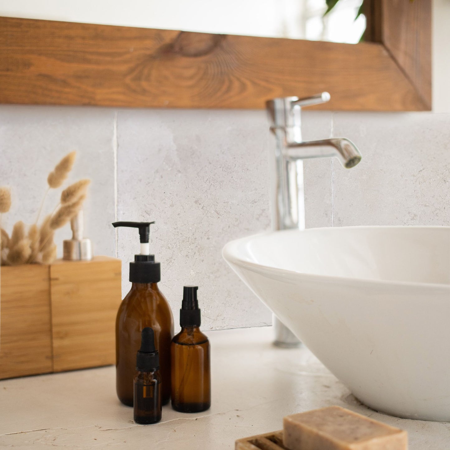 A tiled splashback behind a bathroom sink. The splashback is made up of large cream marble tiles.