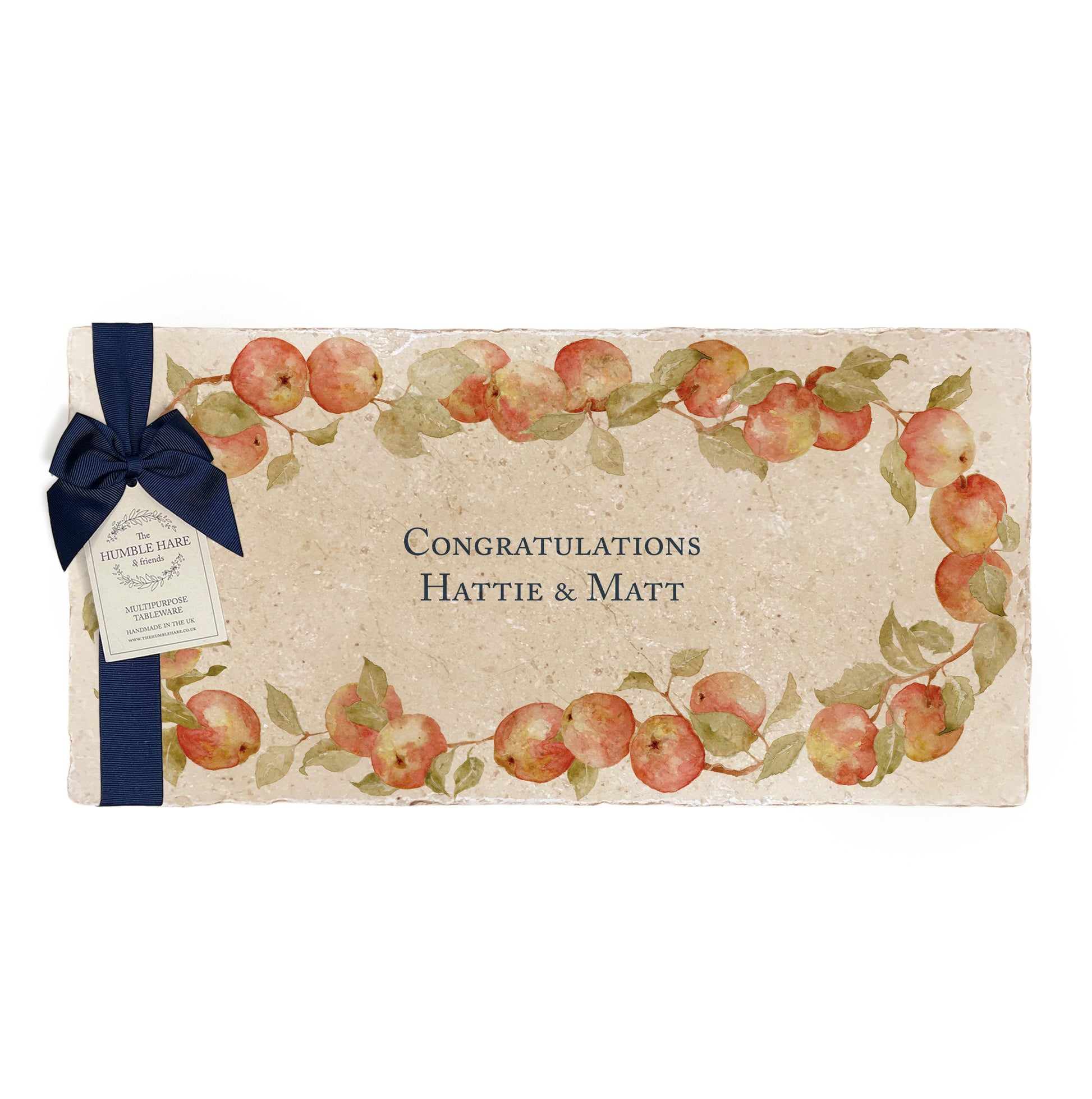 A personalised marble sharing platter featuring a wreath of apples and leaves, with a bespoke message in the centre of the design. The platter is packaged with a luxurious blue gift bow and tag.