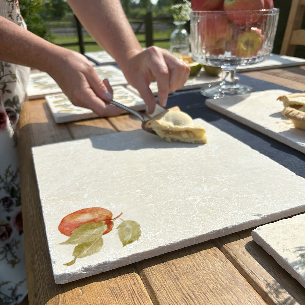 A large marble serving board with a minimalistic apple design, it is being used to serve a slice of apple pie.