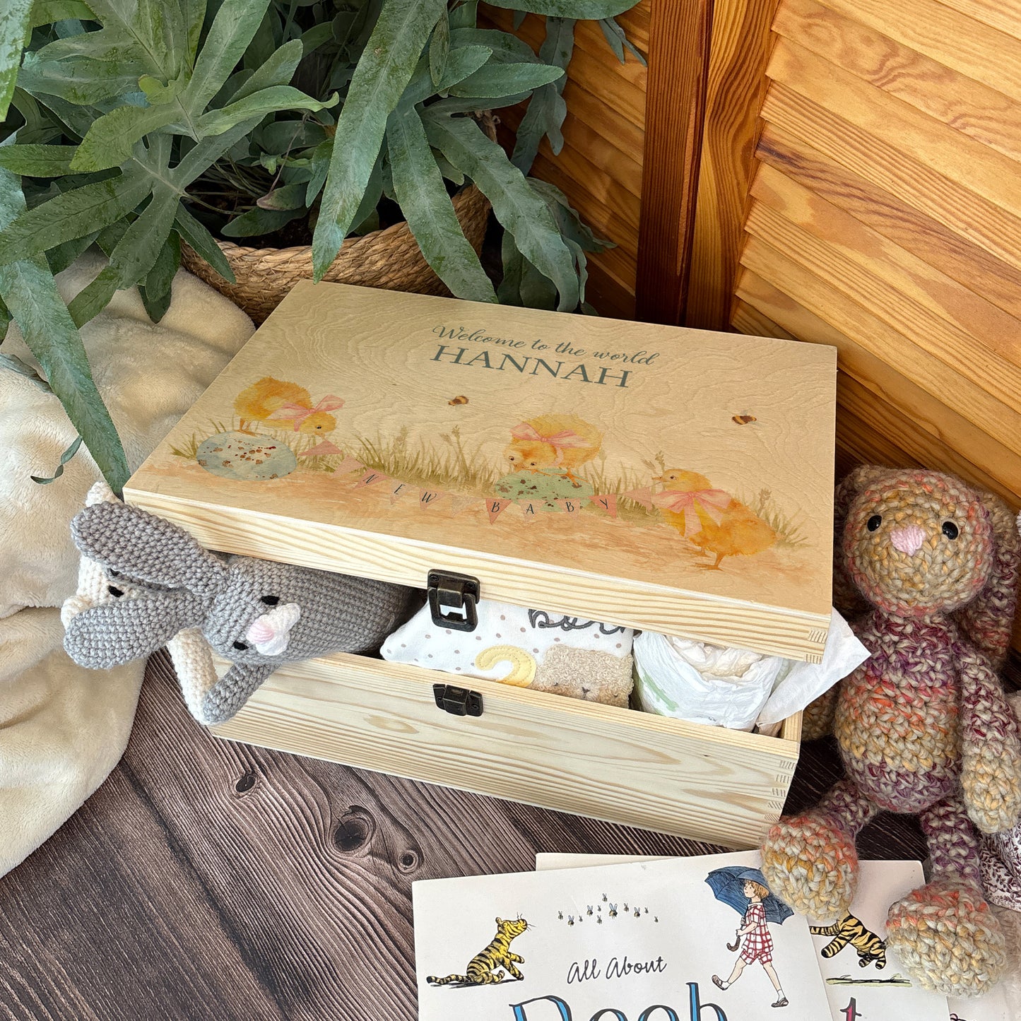Large sized wooden pine personalised keepsake box. The design theme is perfect for New babies, Welcome to the world, baby showers and christenings. The picture also shows an example in a nursey room filled with nappies, vests and teddys.