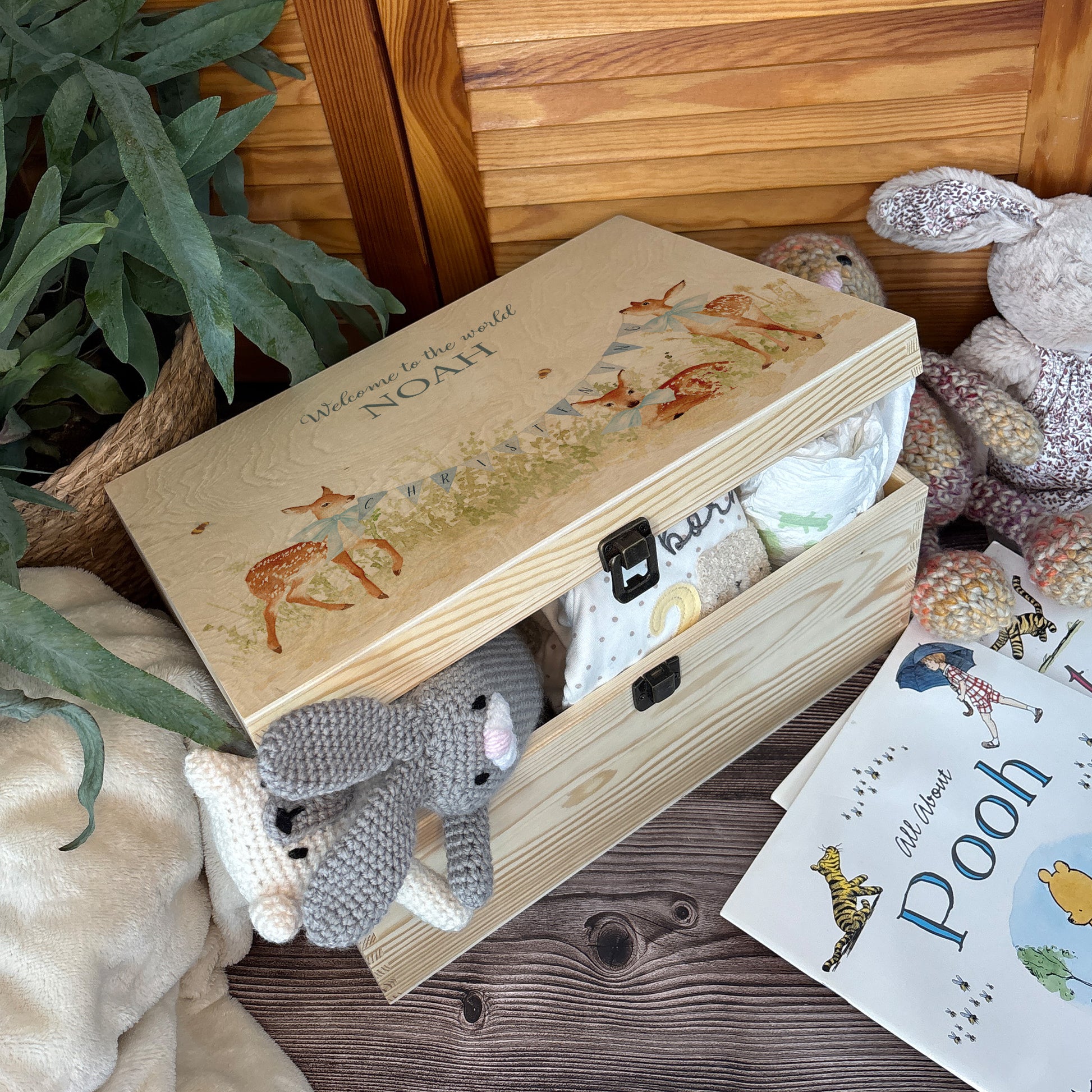 Large sized wooden pine personalised keepsake box. The design theme is perfect for New babies, Welcome to the world, baby showers and christenings. This design has baby Fawns/Deer  in meadow style grass and a buzzy Bee flying around. The picture also shows an example in a nursey room filled with nappies, vests and teddys.