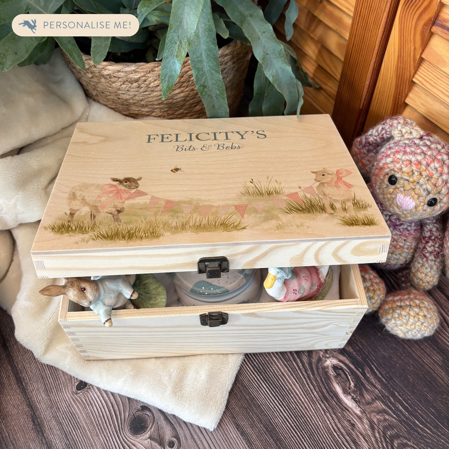 Medium sized wooden pine personalised keepsake box. The design theme is perfect for New babies, Welcome to the world, baby showers and christenings. This design has baby lambs  in playing in grass with a little bee flying around.  This design can be personalised by adding a beautiful bunting and a luxurious bow around their necks in blue or pink. you can also add names , The picture also shows an example in a nursey room filled with nappies, vests and teddys.