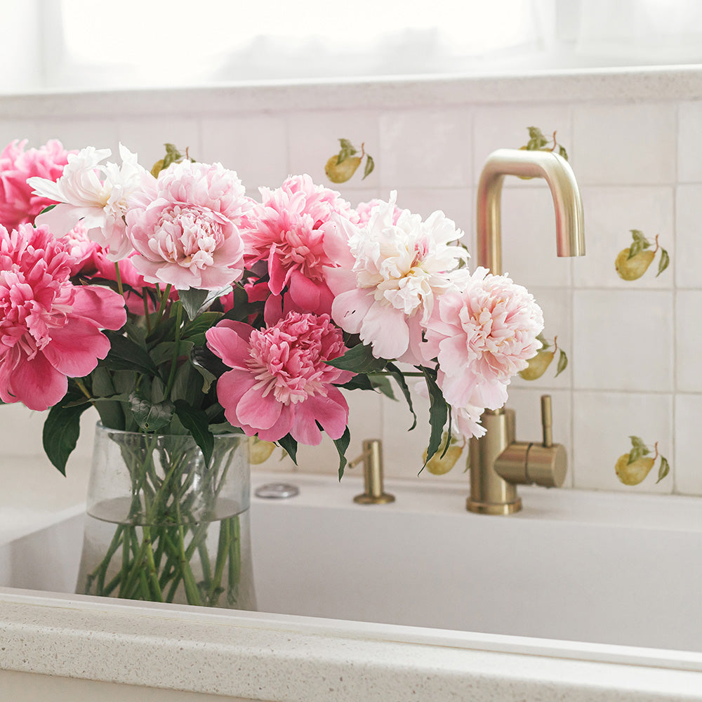 A modern kitchen sink with a splash back of 10x10cm marble tiles featuring a watercolour design of a single pear with leaves.