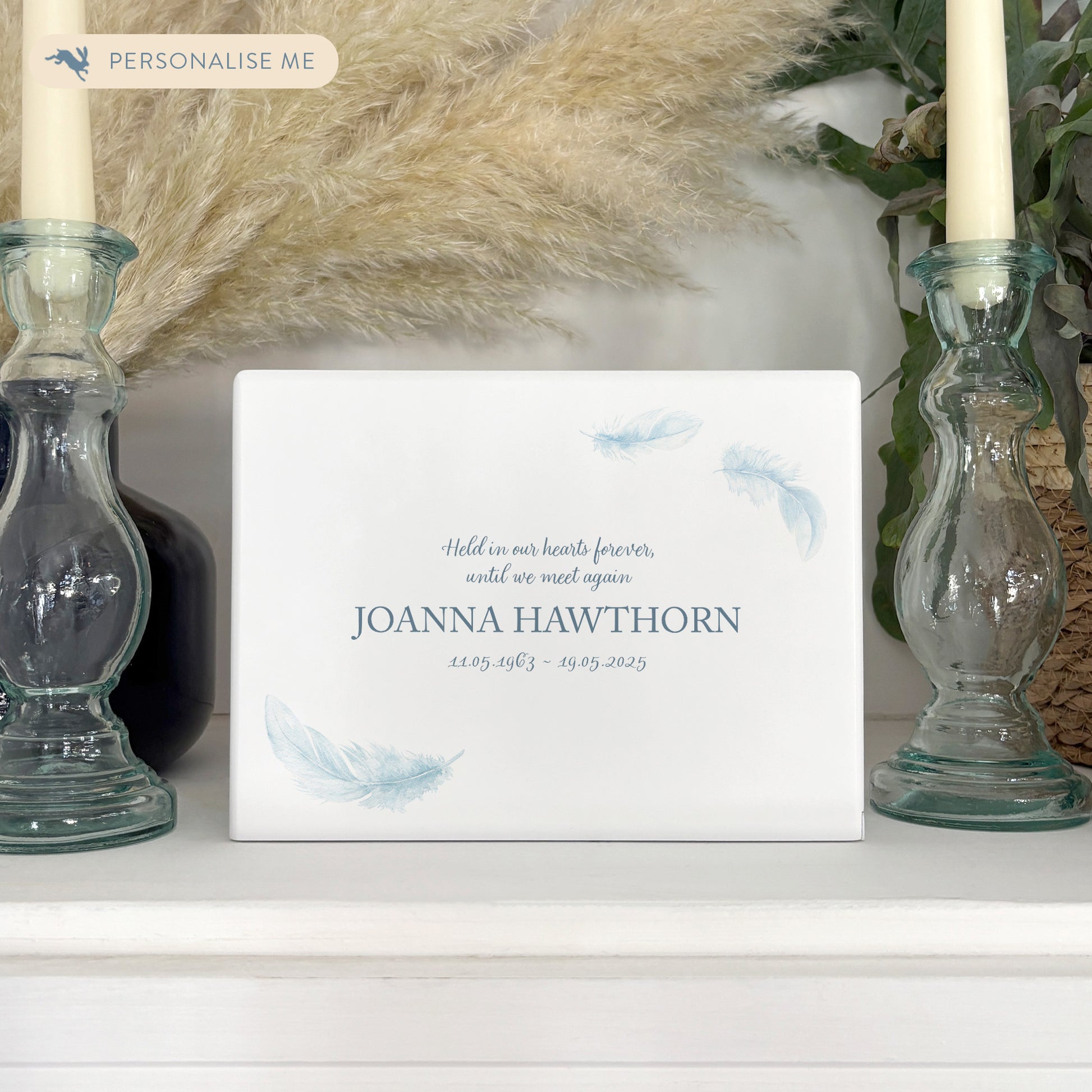 A beautifully crafted solid wooden urn, finished in white with a soft watercolour design of floating Feathers, Thoughtfully made for either display or burial, this personalised urn can be customised to create a meaningful memorial. Perfect for holding ashes of a loved one or a beloved pet, it serves as a comforting tribute and keepsake.