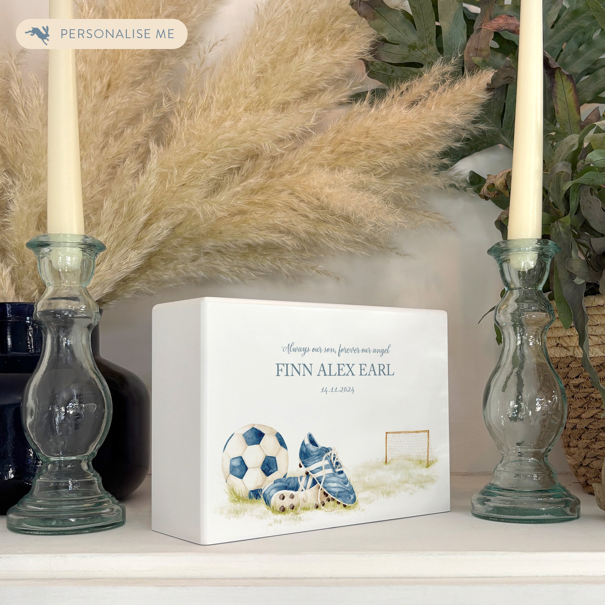 A beautifully crafted solid wooden urn, finished in white with a soft watercolour design of a Football and boots, Thoughtfully made for either display or burial, this personalised urn can be customised to create a meaningful memorial. Perfect for holding ashes of a loved one or a beloved pet, it serves as a comforting tribute and keepsake.