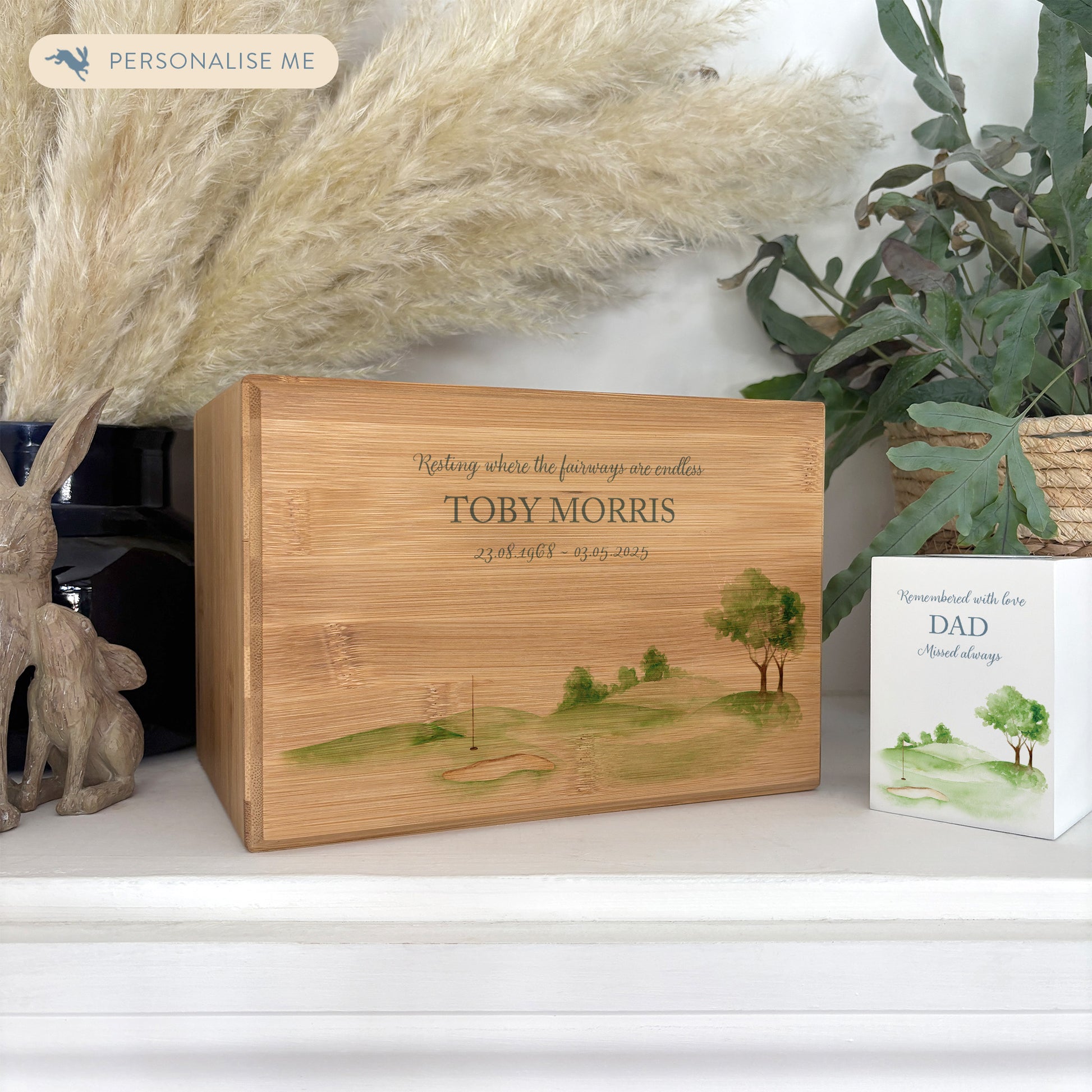 A beautifully crafted solid Bamboo wooden urn, personalised and finished with a soft watercolour design of a golf green, Perfect for the Golf lover- Great for Dad, Grandad, Brother, Son, Uncle.  Thoughtfully made for either display or burial, this personalised urn can be customised to create a meaningful memorial. Perfect for holding ashes of a loved one or a beloved pet, it serves as a comforting tribute and keepsake