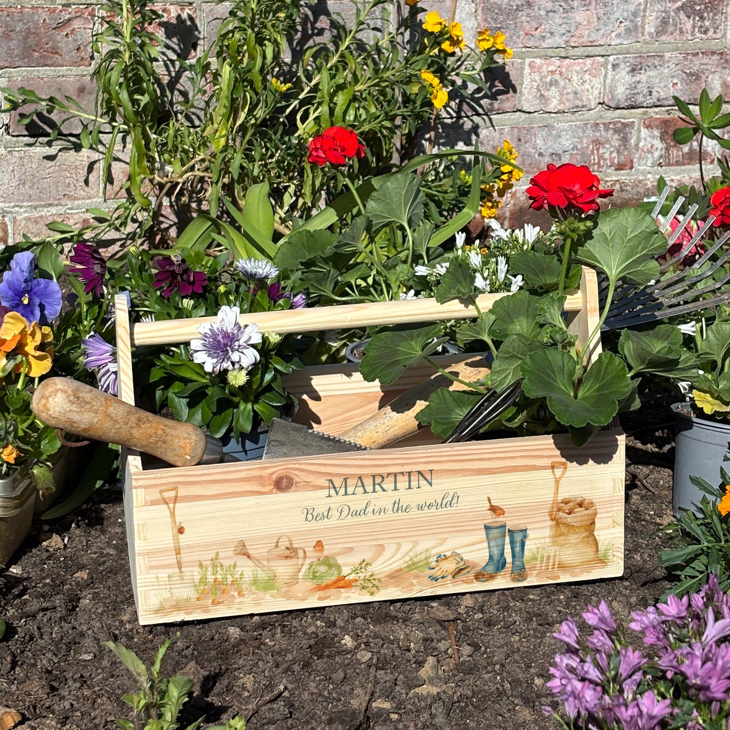 wooden luxury Trug/Caddy the perfect personalised gift. Each product is lovingly designed, handmade with our Countryside inspired watercolour designs. This design features a gardening scene with wellie boots, a sake of potatoes, vegetables, a watering con and a little robin. set in a flower bed unique designs for a truly one off special occasion for a loved one.