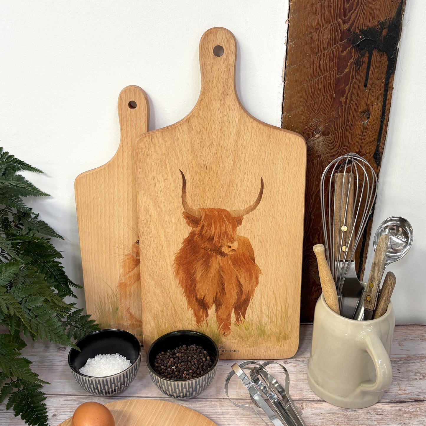 Handmade paddle board in Beech wood, featuring a painted Highland cow with a hand tied luxury blue ribbon.