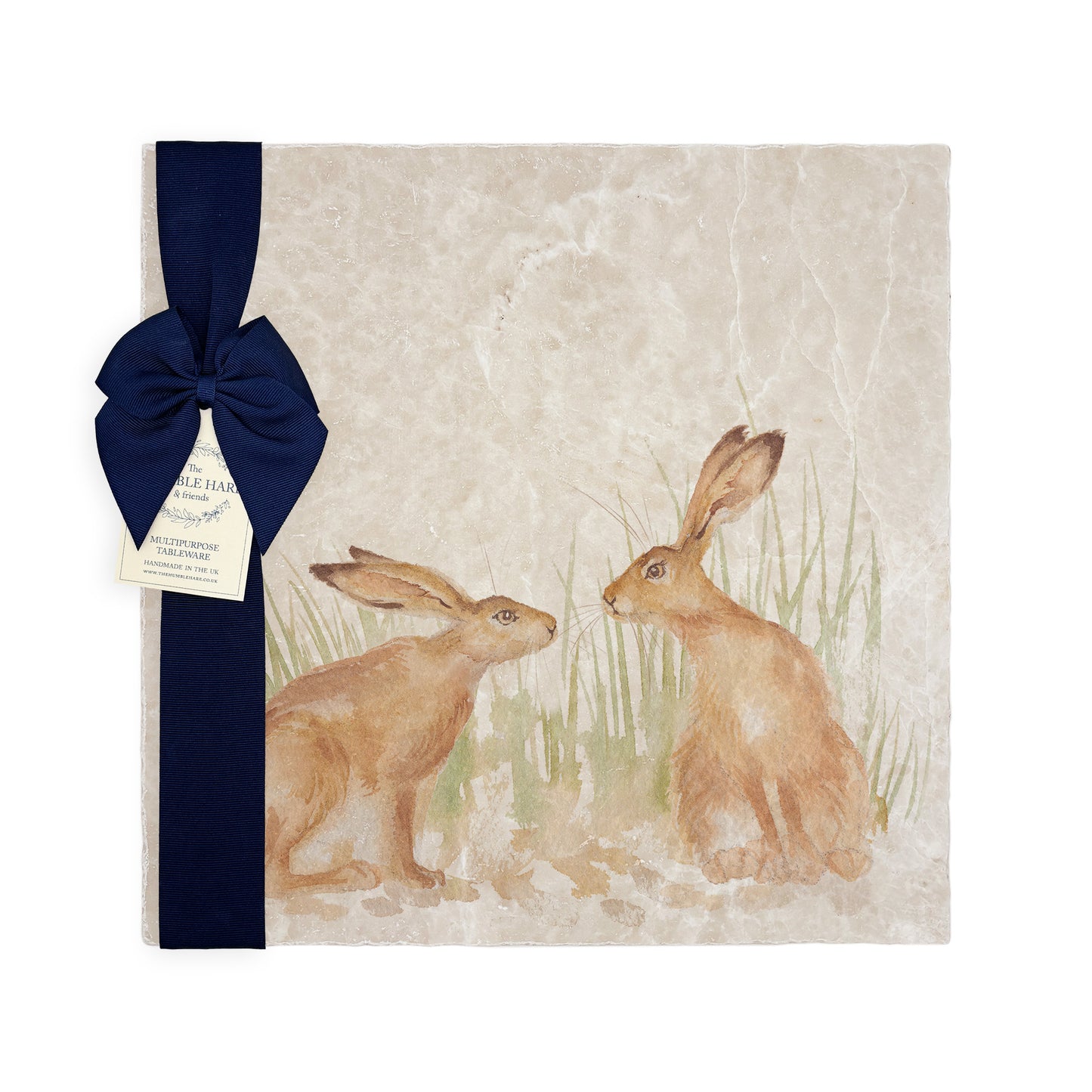 A multipurpose marble platter with a design featuring two hares facing each other about to touch noses, packaged with a luxurious dark blue bow and branded gift tag.