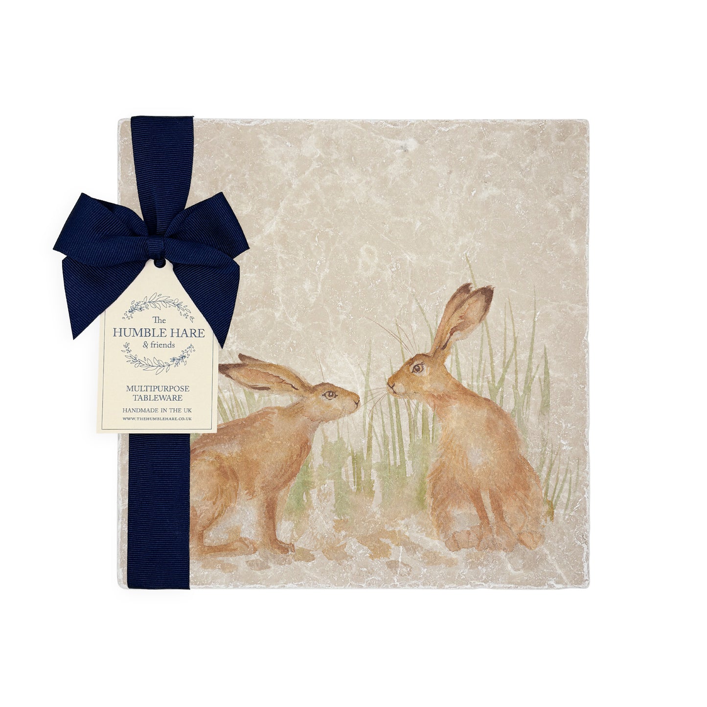 A multipurpose marble platter with a design featuring two hares facing each other about to touch noses, packaged with a luxurious dark blue bow and branded gift tag.