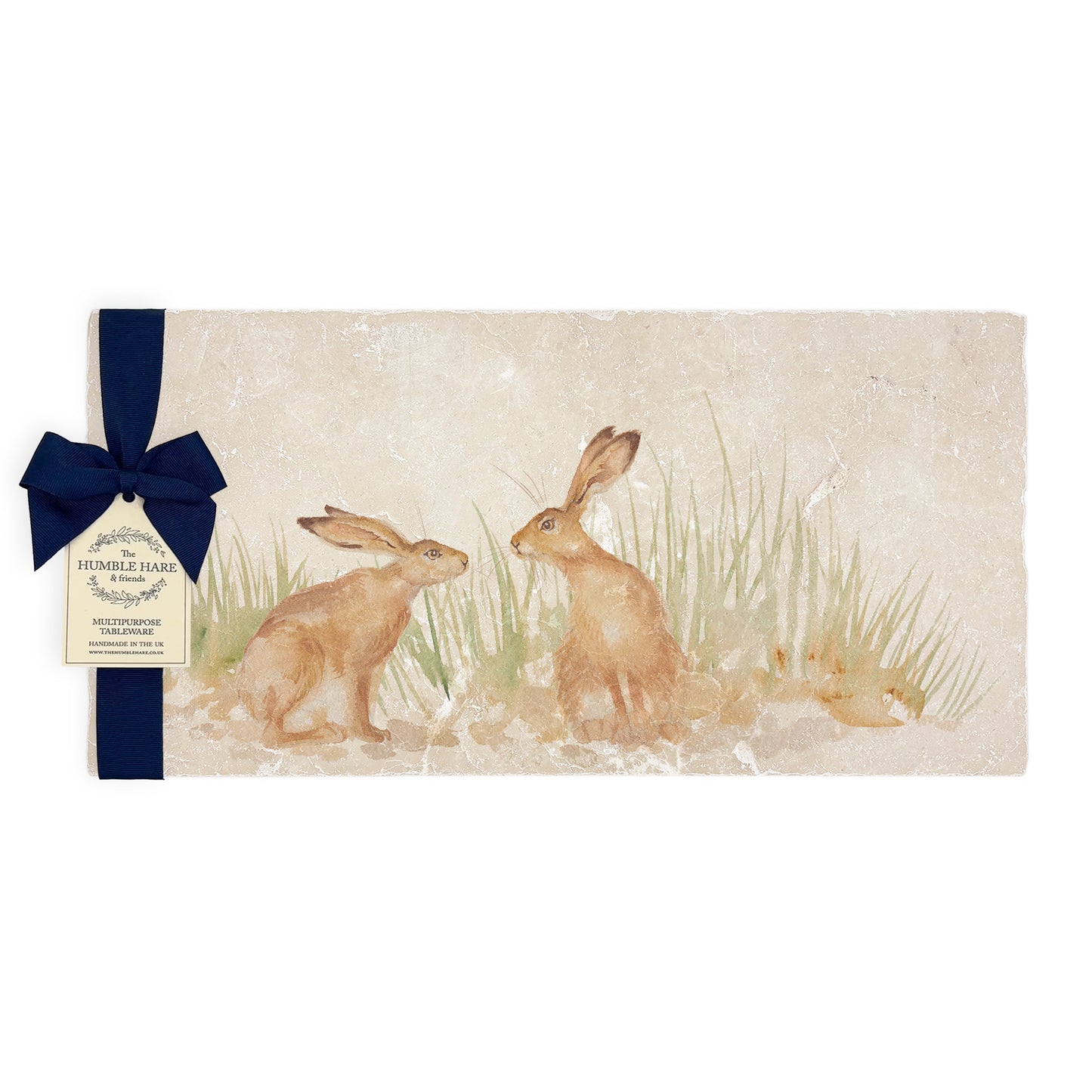 A multipurpose marble platter with a design featuring two hares facing each other about to touch noses, packaged with a luxurious dark blue bow and branded gift tag.