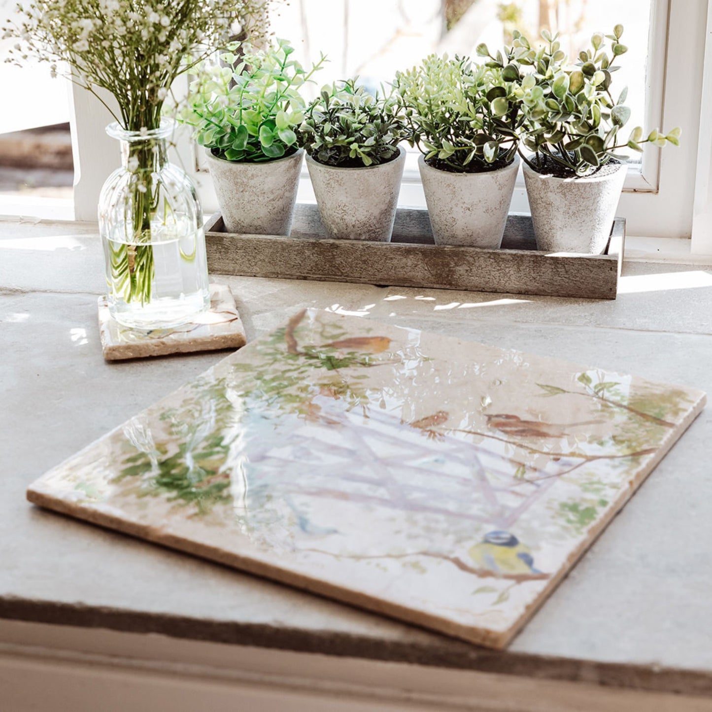 A large marble platter with a watercolour design featuring British garden birds in the hedgerow around the paddock gate.