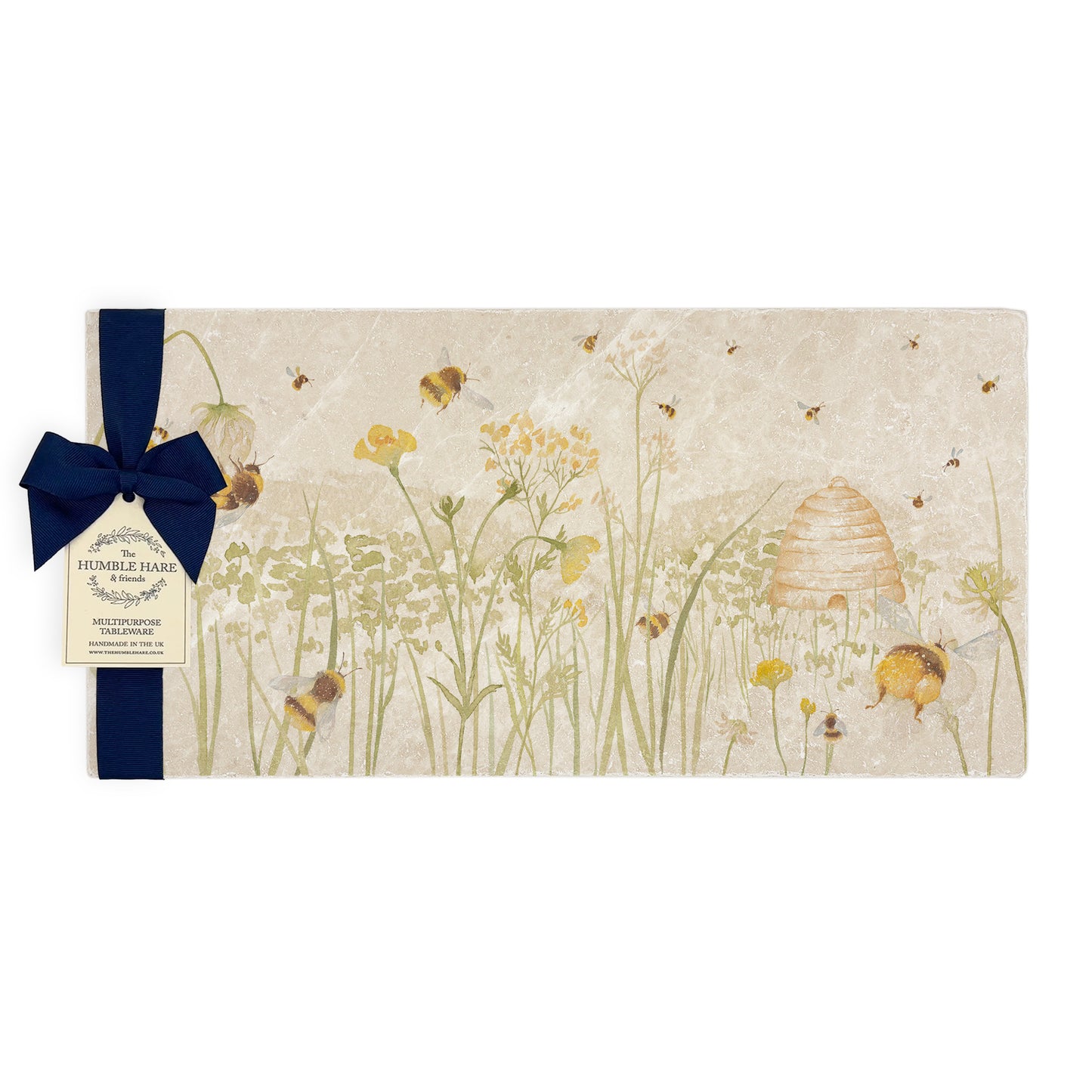 A multipurpose marble platter with a watercolour design featuring bees and a beehive in a buttercup meadow, packaged with a luxurious dark blue bow and branded gift tag.
