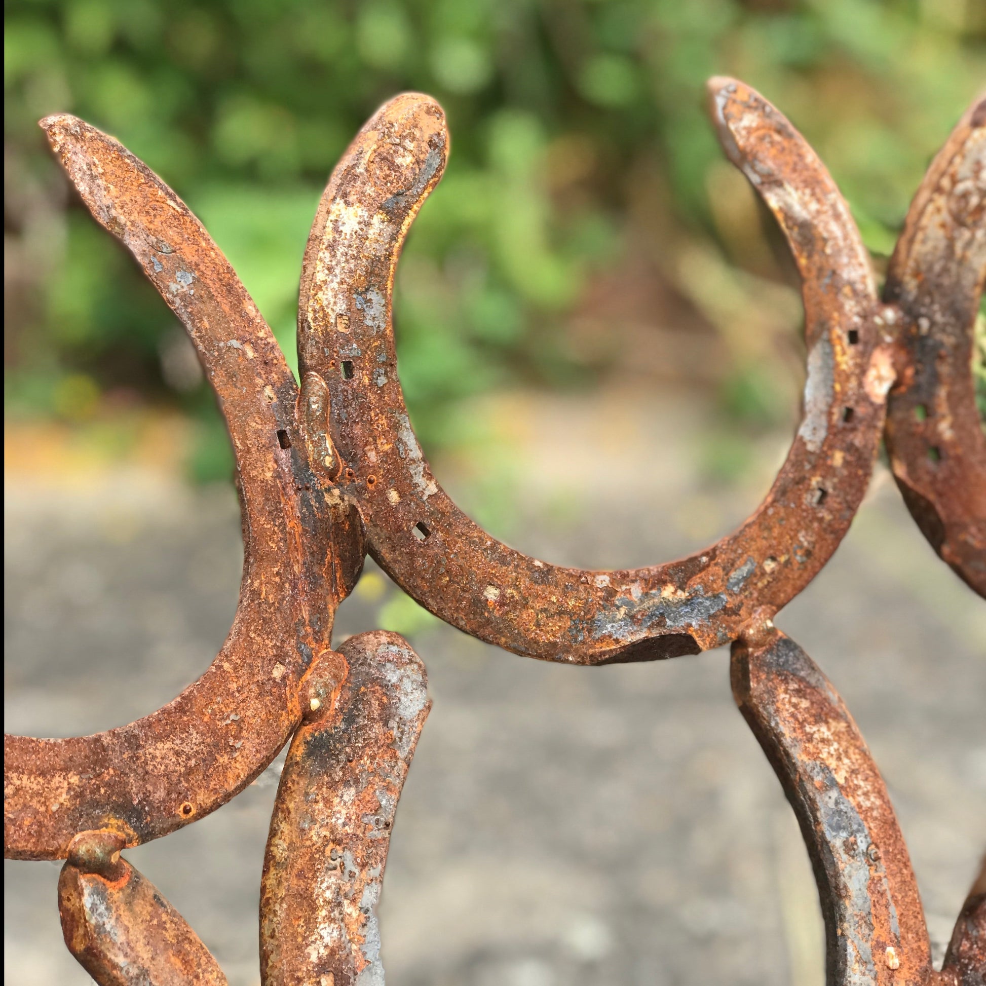 A closeup of horseshoes forming a handmade fire pit. The horseshoes have an authentic rust finish.
