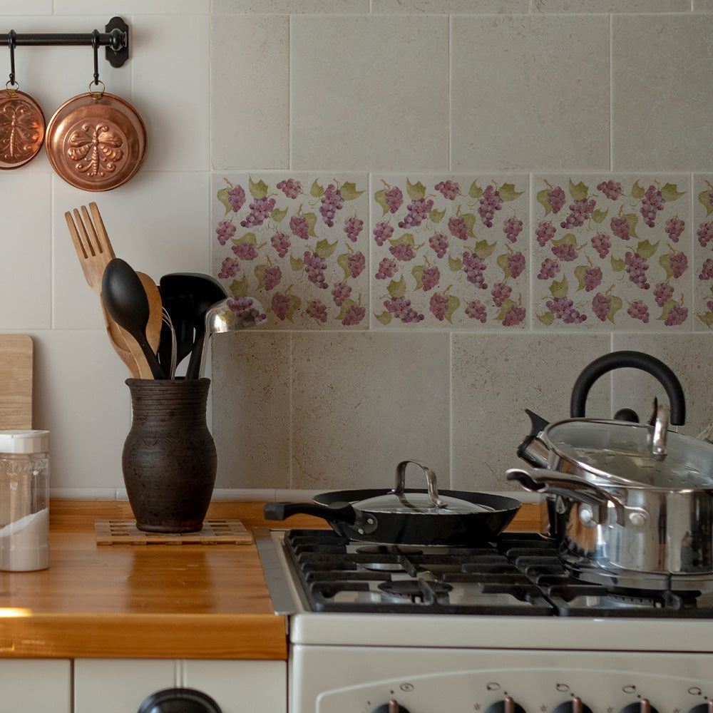 A rustic country kitchen with a hob splash back made up of 20x20cm cream marble tiles featuring a maximalist pattern of purple grapes.