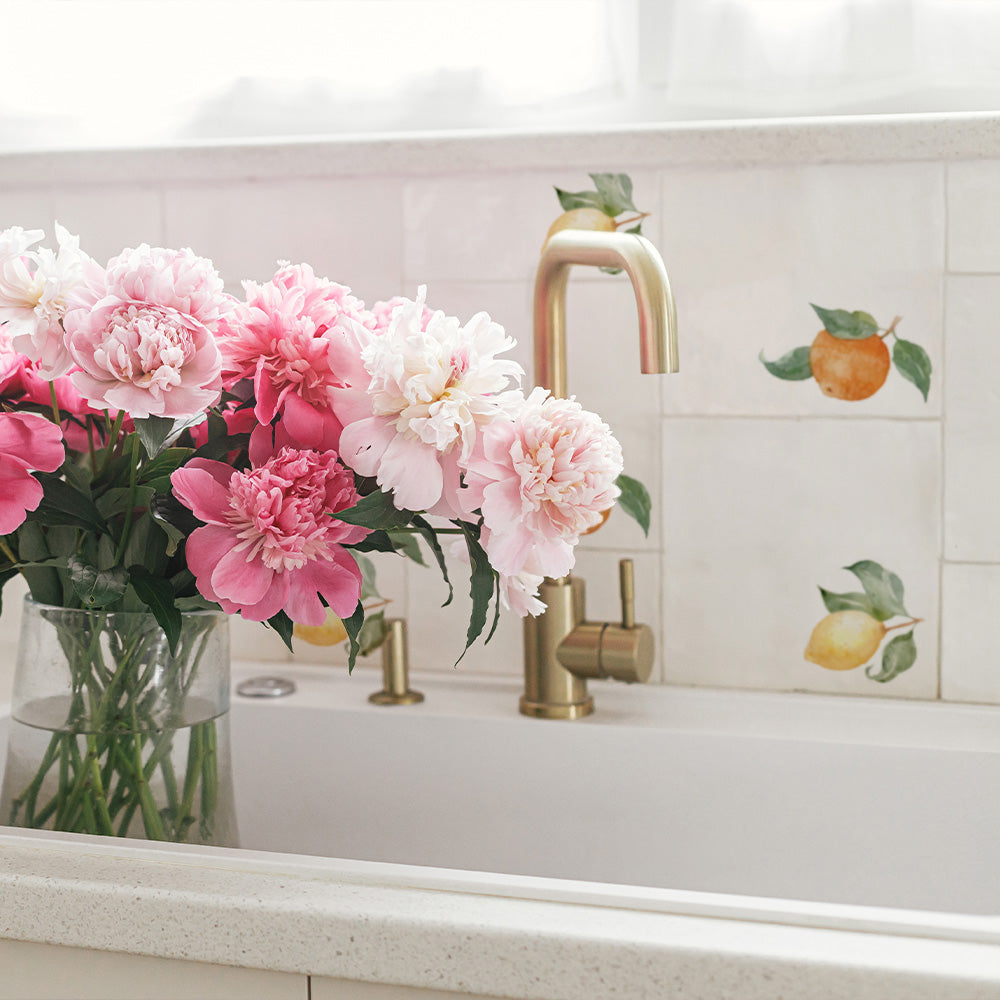 A modern kitchen with a sink splash back made up of 20x20cm marble tiles in an alternating pattern of watercolour lemons and oranges.