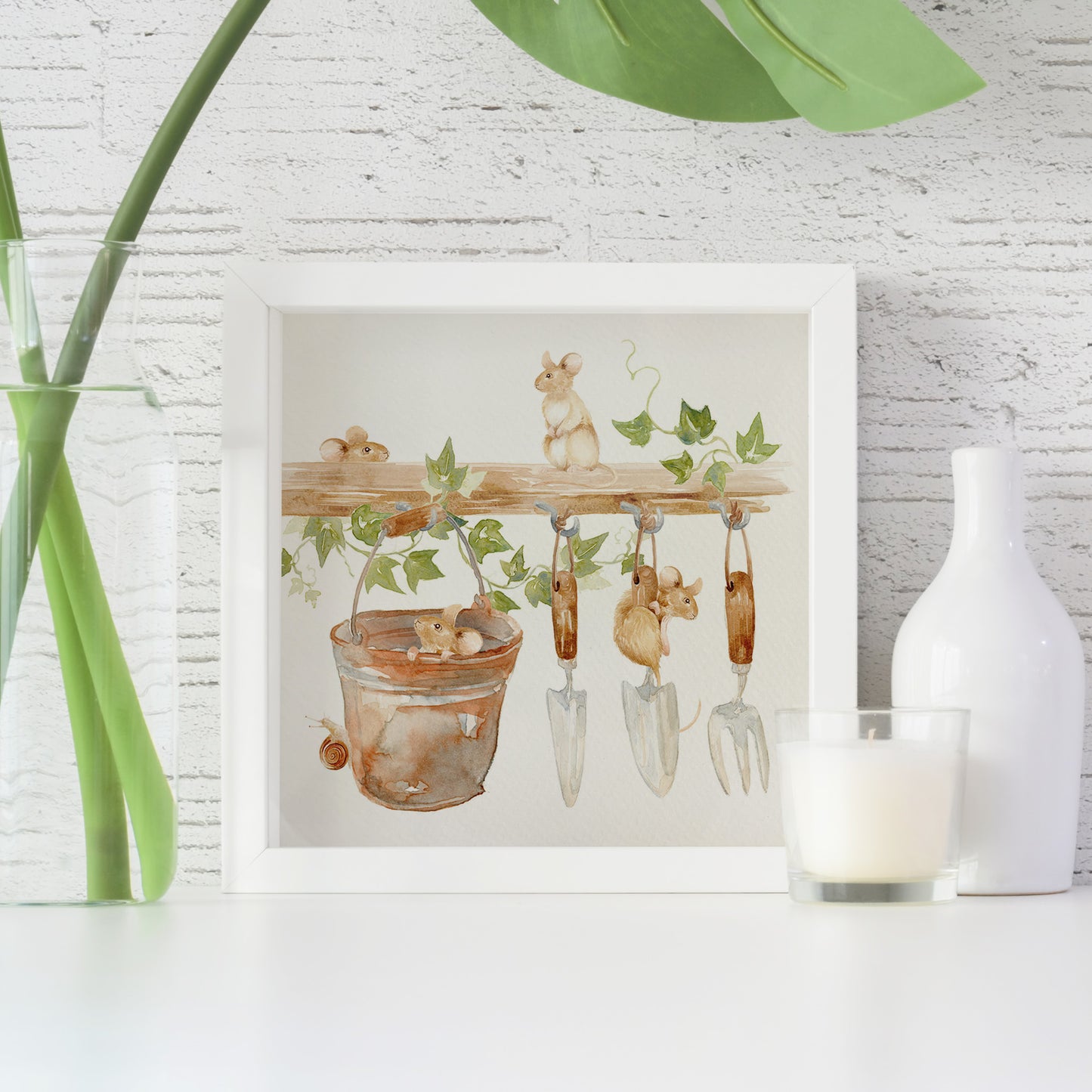 A framed greetings card with a watercolour scene of dormice in the garden shed.