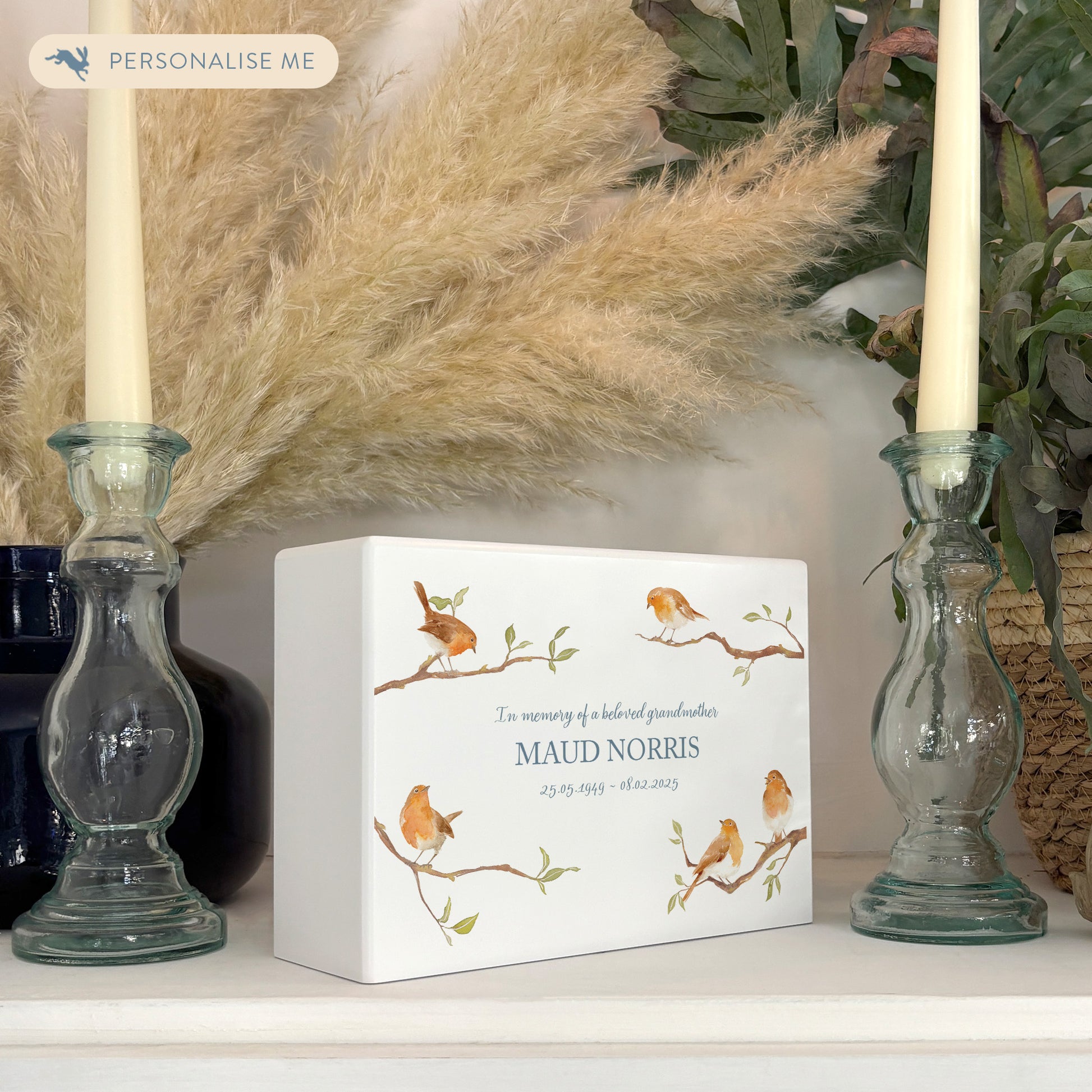 A beautifully crafted solid wooden urn, finished in white with a soft watercolour design of Robins on Branches,  Thoughtfully made for either display or burial, this personalised urn can be customised to create a meaningful memorial. Perfect for holding ashes of a loved one or a beloved pet, it serves as a comforting tribute and keepsake.