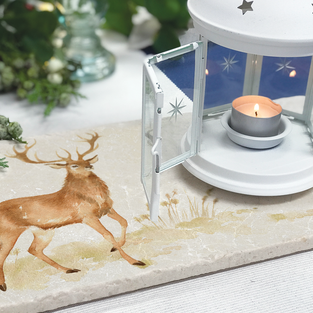 A rectangle marble sharing platter featuring a majestic stag in watercolour. It is being used as a table centrepiece with a candle holder set upon it.
