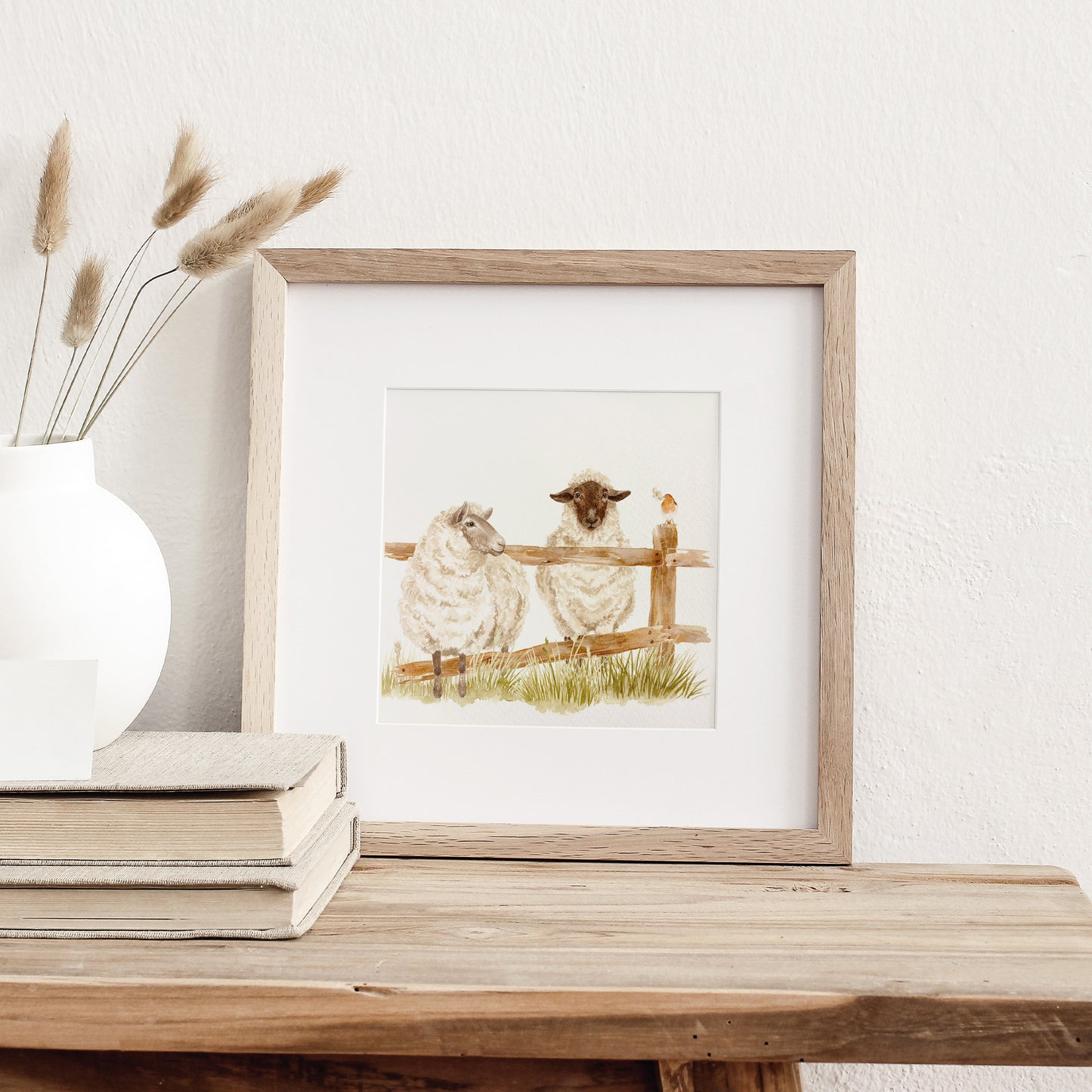 A framed greetings card featuring a watercolour design of two sheep escaping through a broken fence.