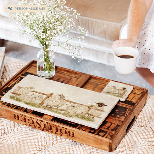 A rectangle marble sharing platter, featuring a watercolour design of five sheep escaping from their field, set on a coffee table.
