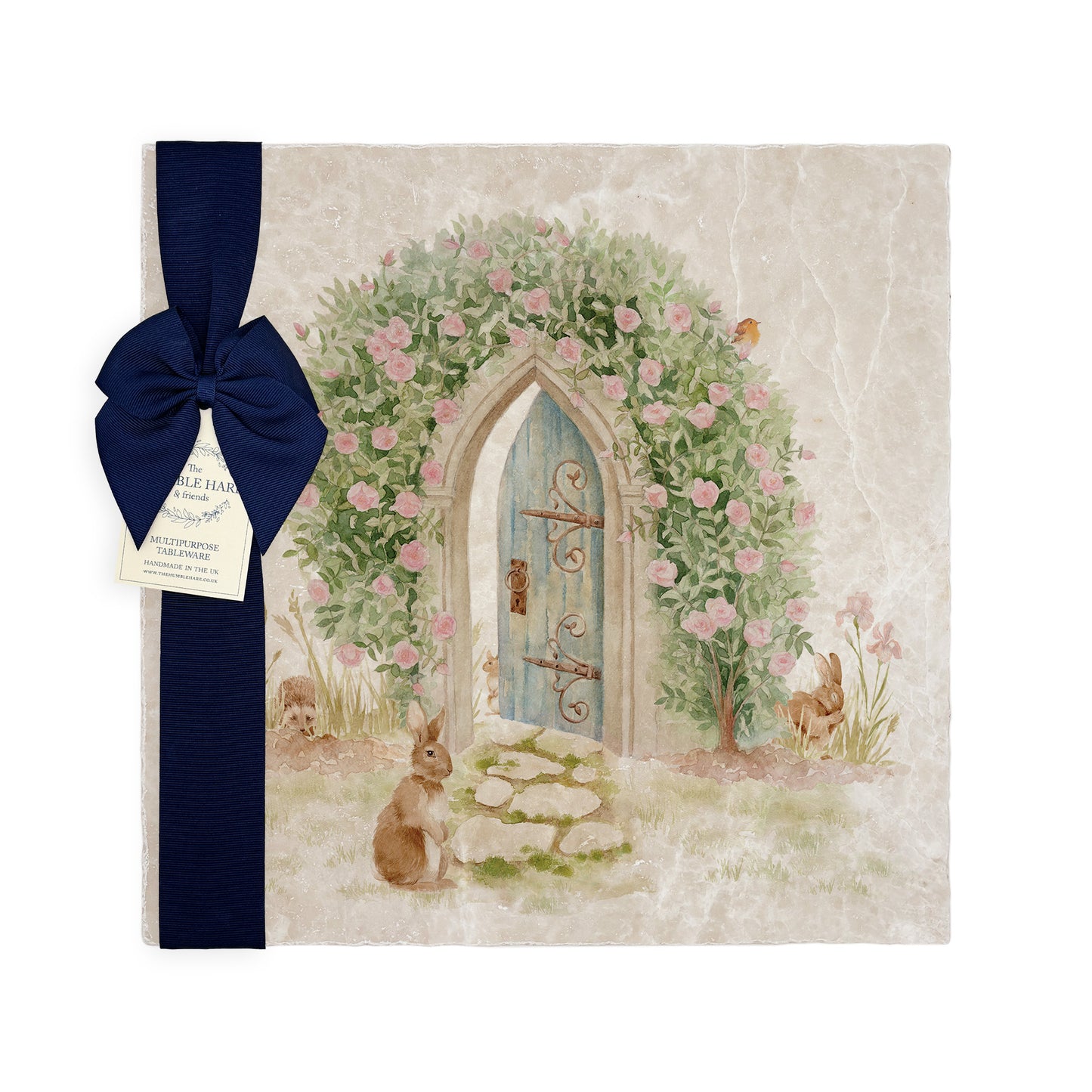A large multipurpose marble platter with a watercolour design of a hidden door under a rose archway that leads to a secret garden, packaged with a luxurious dark blue bow and branded gift tag.