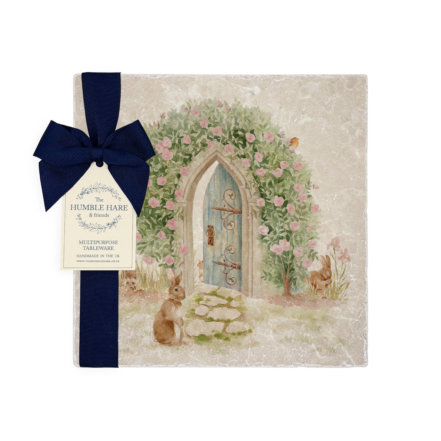 A medium multipurpose marble platter with a watercolour design of a hidden door under a rose archway, packaged with a luxurious dark blue bow and branded gift tag.