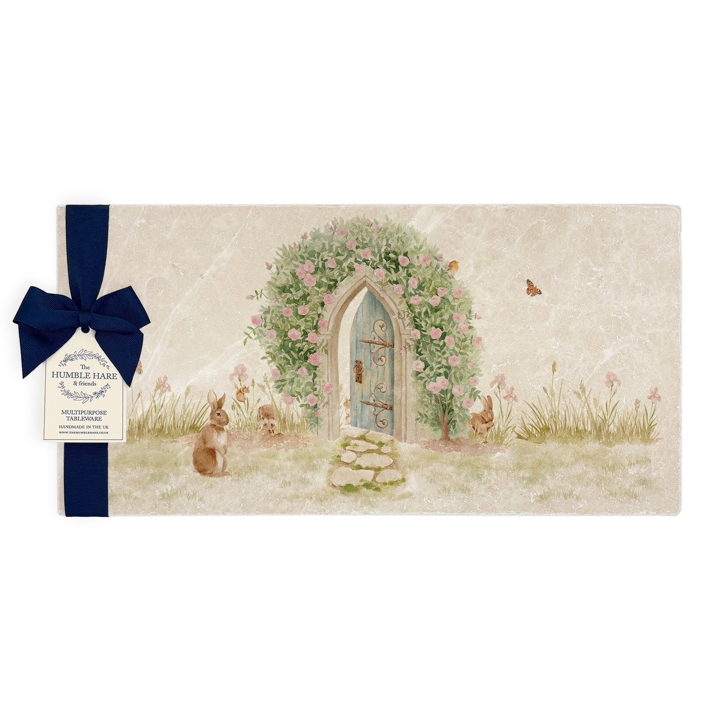 A multipurpose marble sharing platter with a watercolour scene of rabbits and mice leading you to a hidden garden door, packaged with a luxurious dark blue bow and branded gift tag.
