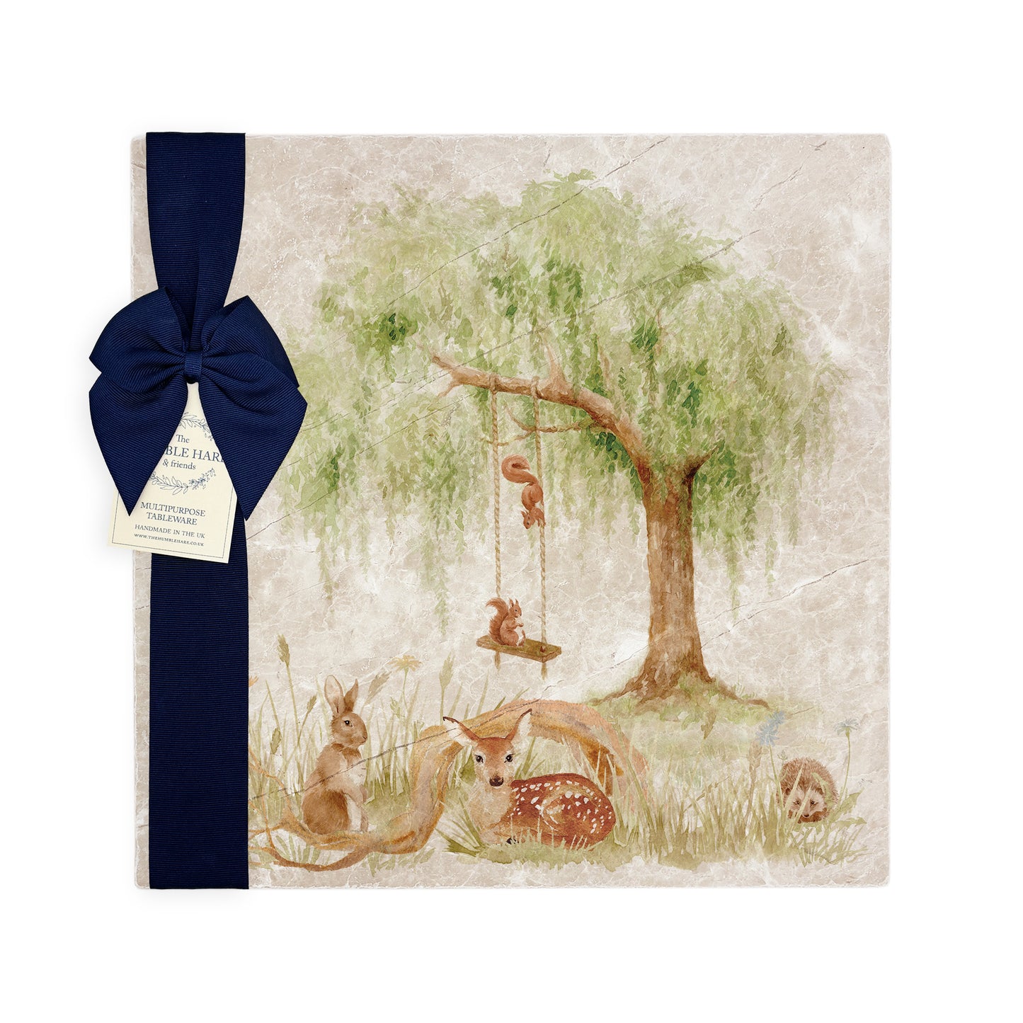 A large multipurpose marble platter with a watercolour scene of woodland animals underneath a willow tree, packaged with a luxurious dark blue bow and branded gift tag.