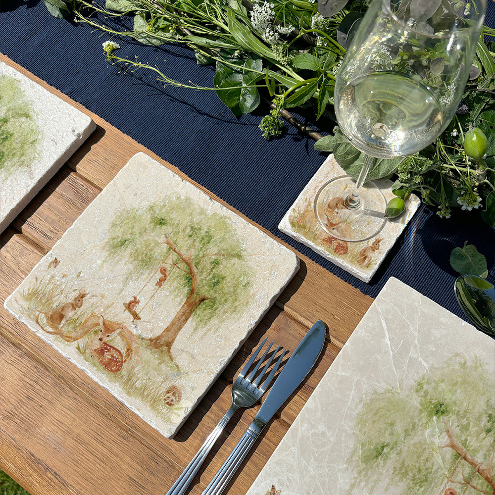 A medium marble platter featuring a watercolour scene of woodland animals underneath a willow tree. The platter is set on a garden table with matching placemats and coasters.