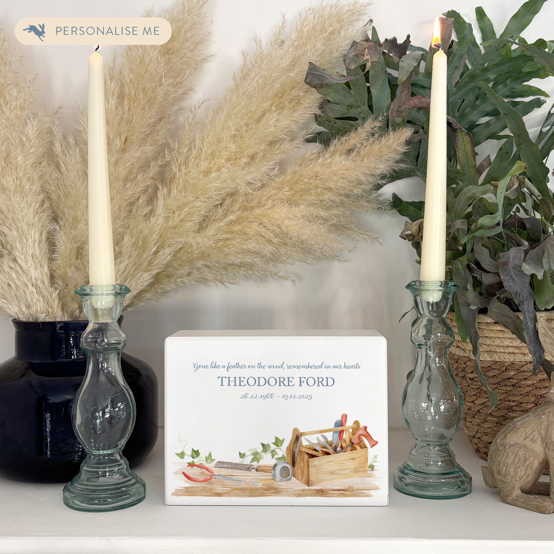 A beautifully crafted solid wooden urn, finished in white with a soft watercolour design of a Tool box on a shelf, perfect for Dad, brother, uncle, Grandad who loved his workshop. Thoughtfully made for either display or burial, this personalised urn can be customised to create a meaningful memorial. Perfect for holding ashes of a loved one or a beloved pet, it serves as a comforting tribute and keepsake.