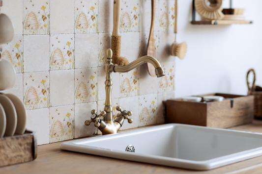 Square marble tiles behind a country kitchen sink. The tiles alternate between plain and a watercolour bee design.