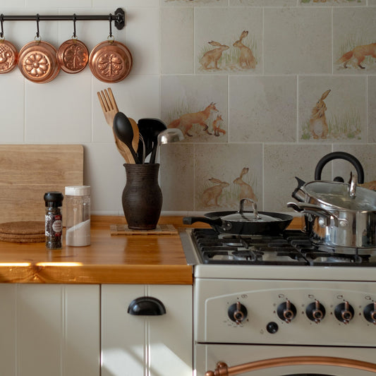 A tiled splashback behind an oven in a country farmhouse kitchen. The splashback is made up of plain marble tiles, alternated with marble tiles featuring countryside animals including hares and foxes.