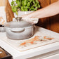 A country kitchen worksurface protected by a multipurpose marble platter that features a fox and fox cub watercolour design. The platter is being used as a trivet for a casserole dish.