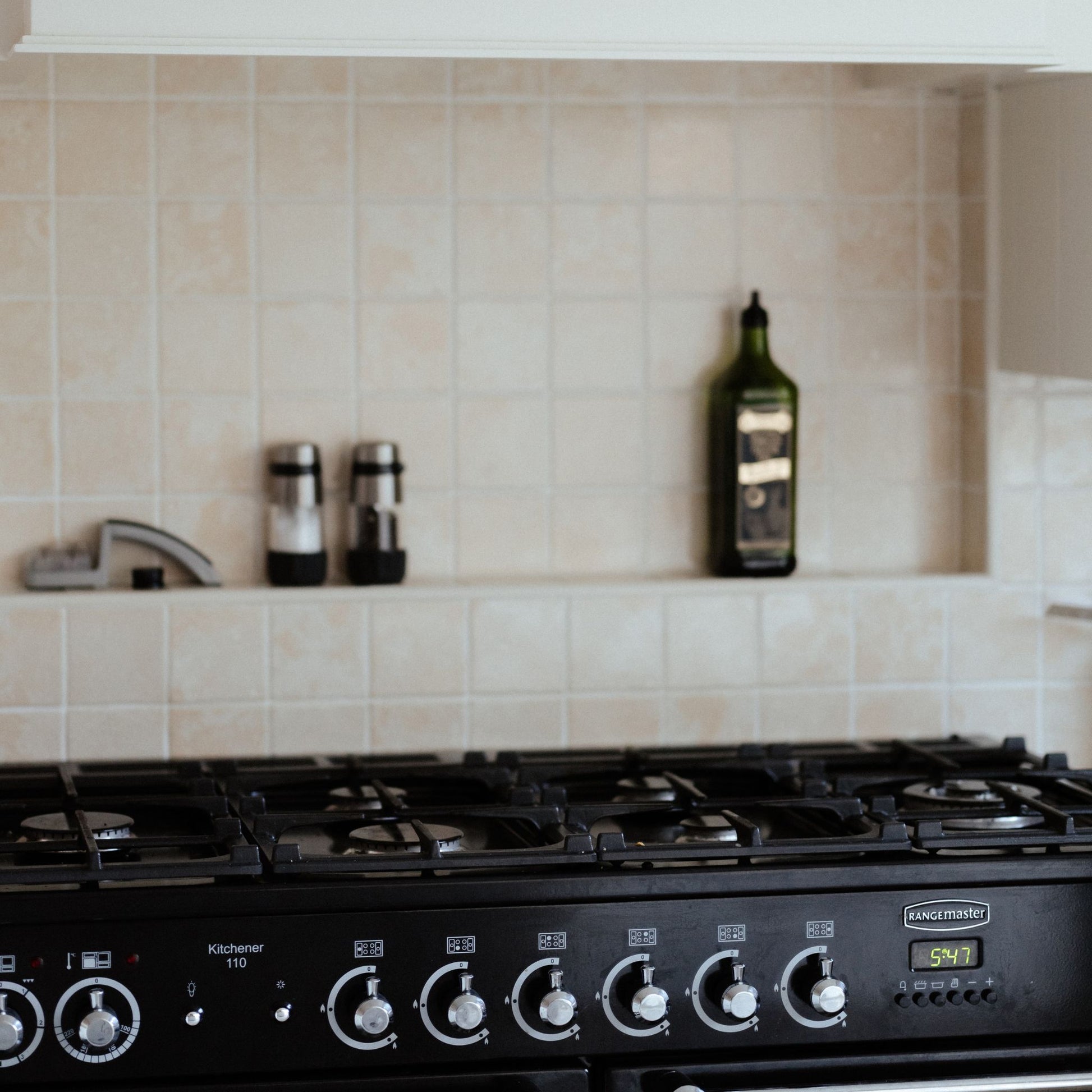 A tiled splashback behind a rangemaster oven in a country kitchen. The splashback is made up of small plain cream marble tiles.