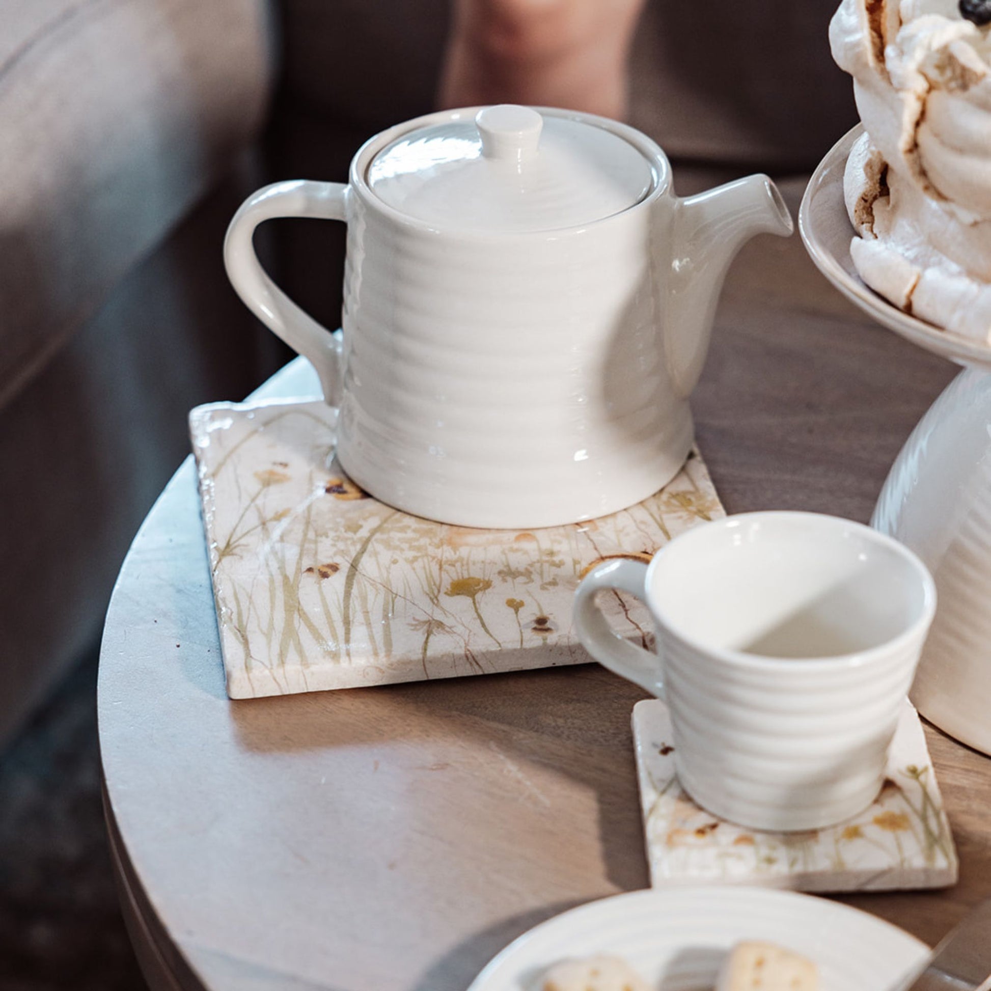 A medium marble platter with a bee and beehive design, the platter is being used as a teapot stand.