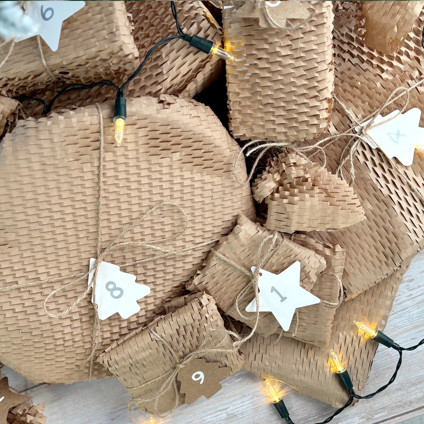 A 12 Days of Christmas homeware Advent Calendar under the tree, with each gift wrapped in rustic brown paper and twine, with numbered labels.