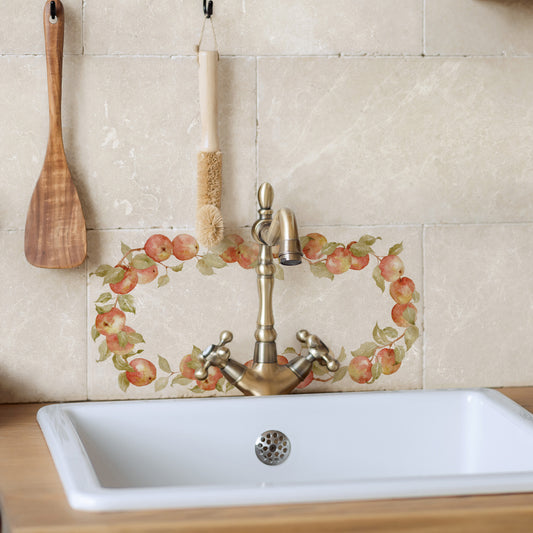 A rectangle marble splashback tile with an apple wreath design, set behind a country kitchen sink.