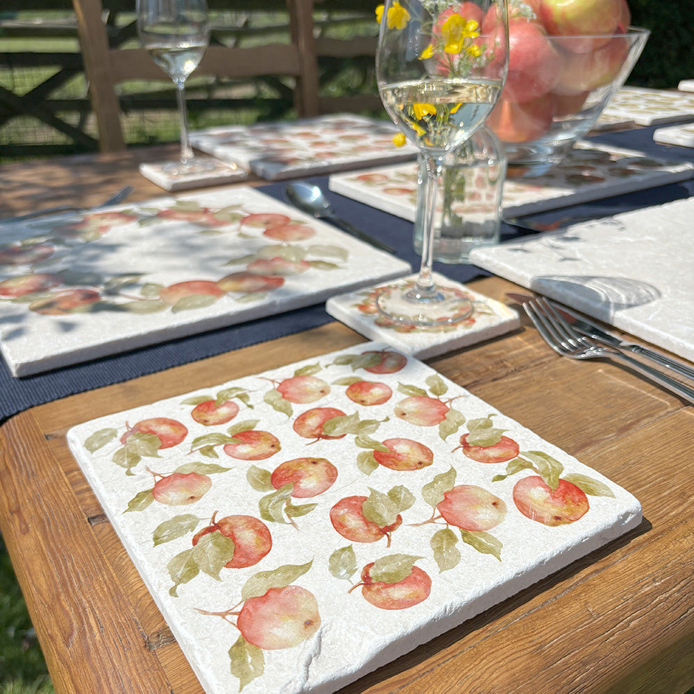 A sunny dinner table set with handmade marble platters featuring a watercolour pattern inspired by English apple orchards.