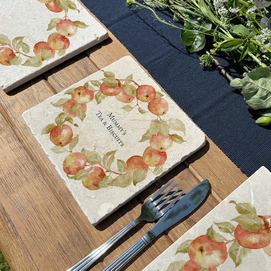 A medium marble serving board personalised with the bespoke message ‘Mummy’s Tea & Biscuits’. The serving board is set on a table in a sunny garden.