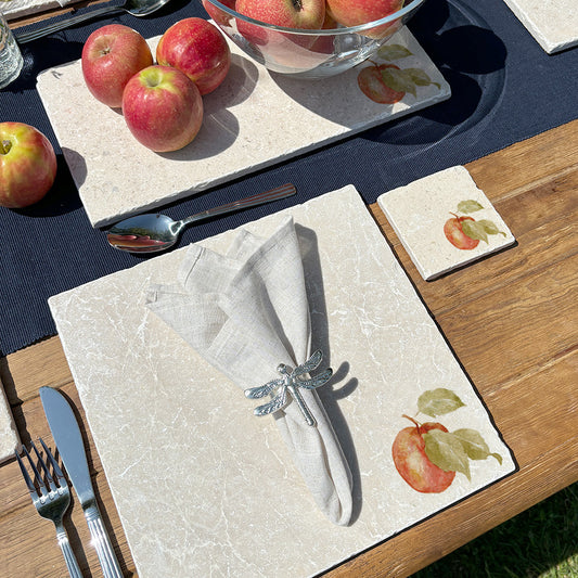 An elegant dining table set with marble placemats and coasters featuring a minimalistic apple design.