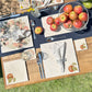 A garden table set with marble placemats and coasters that feature a watercolour apple design.