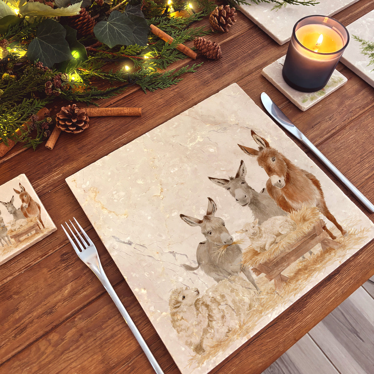 A large square marble platter featuring a rustic nativity scene illustration with three donkeys, a sheep, and a baby lamb in a wooden manger.