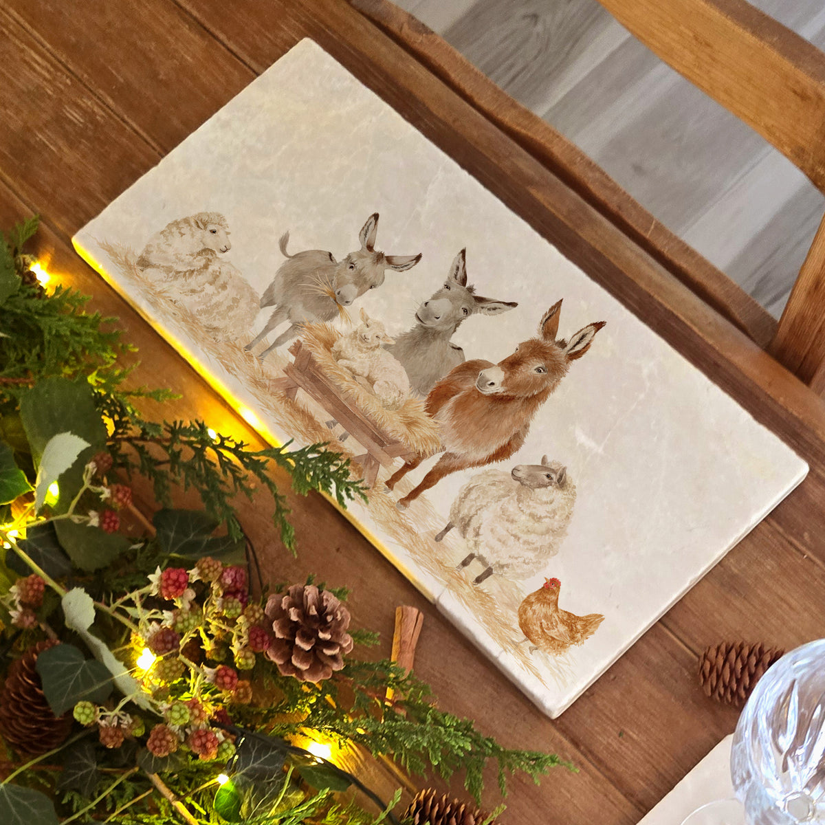 A rectangular marble sharing platter featuring a nativity scene with donkeys, sheep, a chicken, and a lamb in a manger,