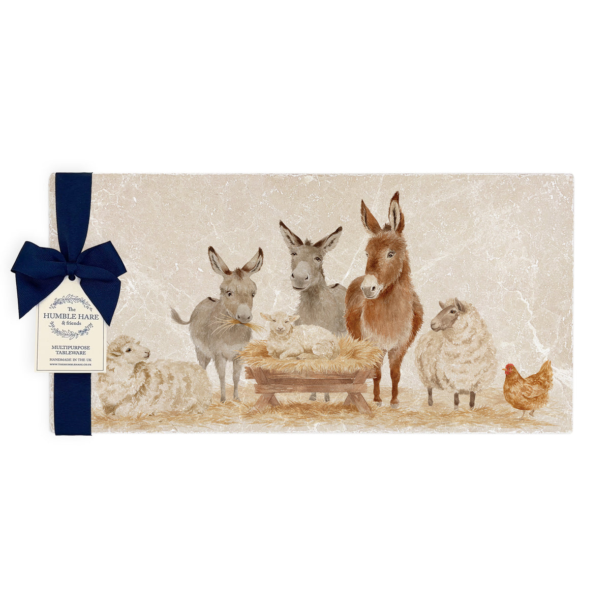 A rectangular marble sharing platter featuring a nativity scene with donkeys, sheep, a chicken, and a lamb in a manger, with a navy ribbon and small hanging tag tied to the left side.