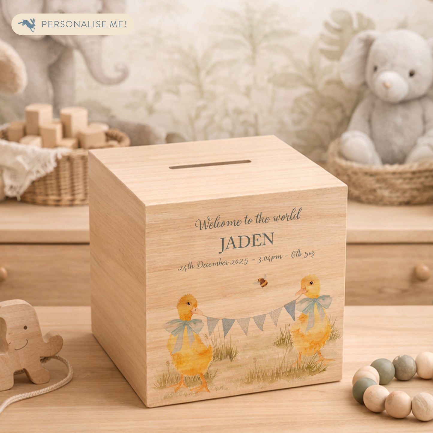 watercolour themed handmade money box for new baby nursery gift, yellow ducklings playing in the field , holding onto bunting with bows around their necks 