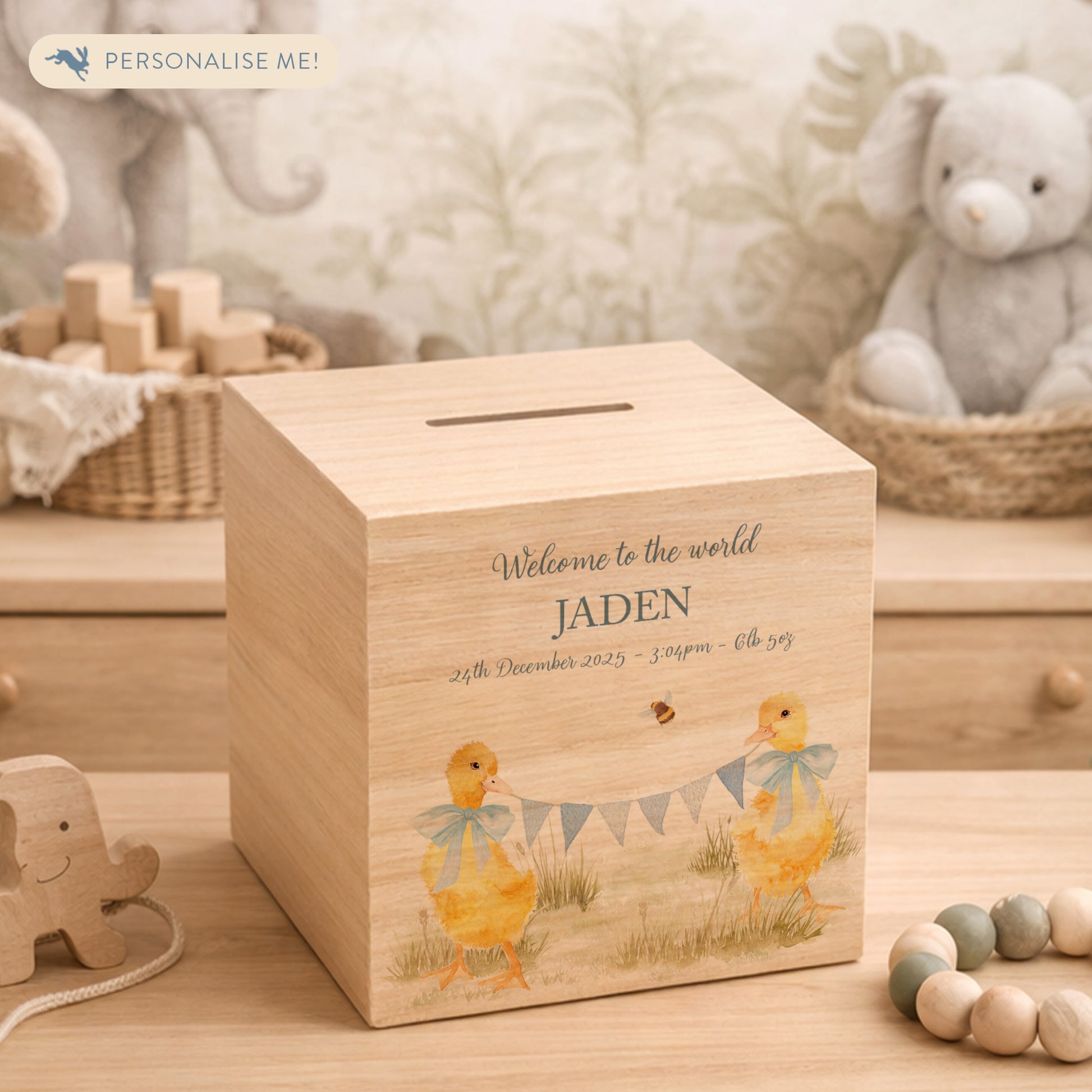 watercolour themed handmade money box for new baby nursery gift, yellow ducklings playing in the field , holding onto bunting with bows around their necks 