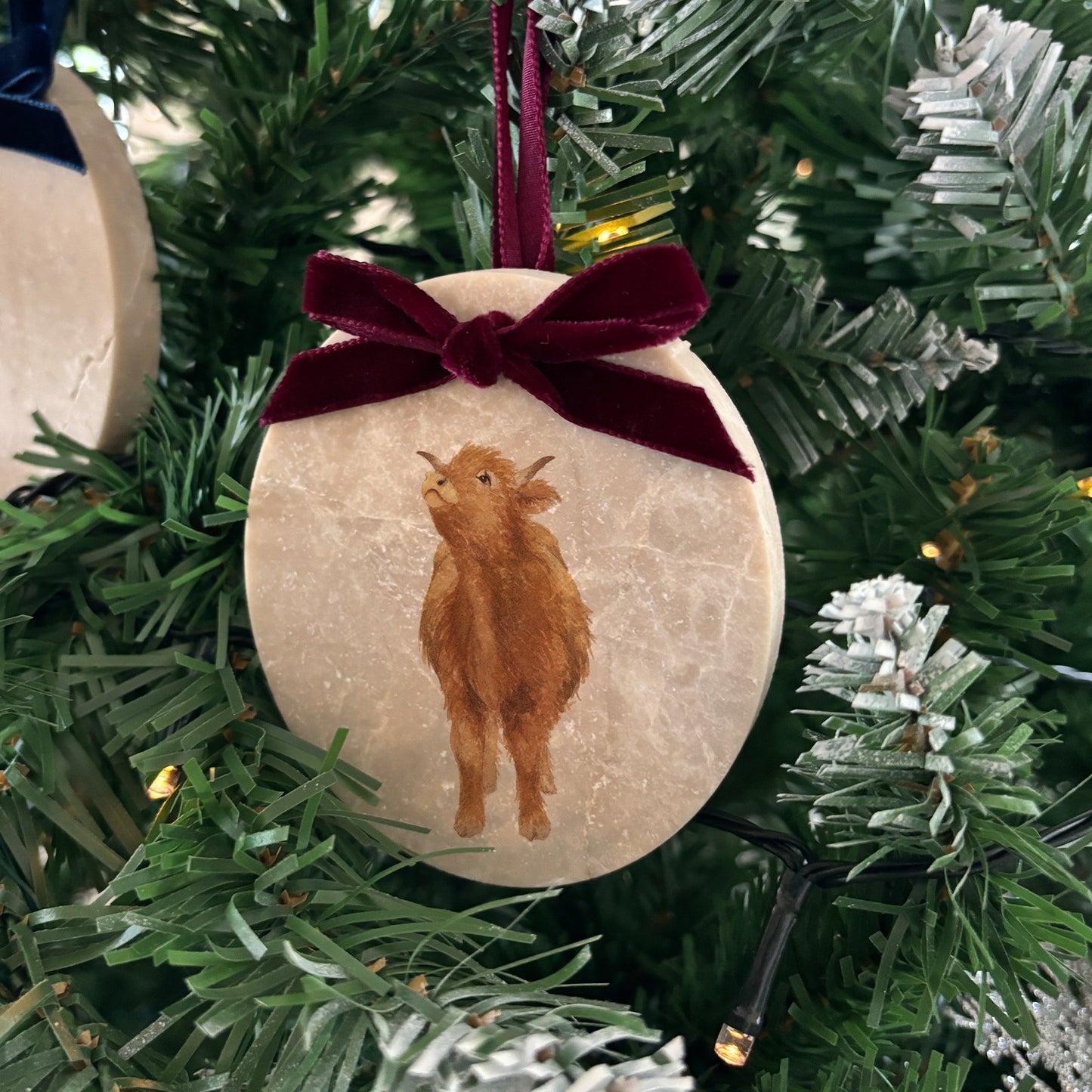 Our oval-shaped marble Christmas bauble combines our cute Highland calf design with a personalised touch. Available with various velvet ribbon colours, these beautifully crafted baubles are the perfect way to add a bespoke, nature-inspired accent to your festive décor.