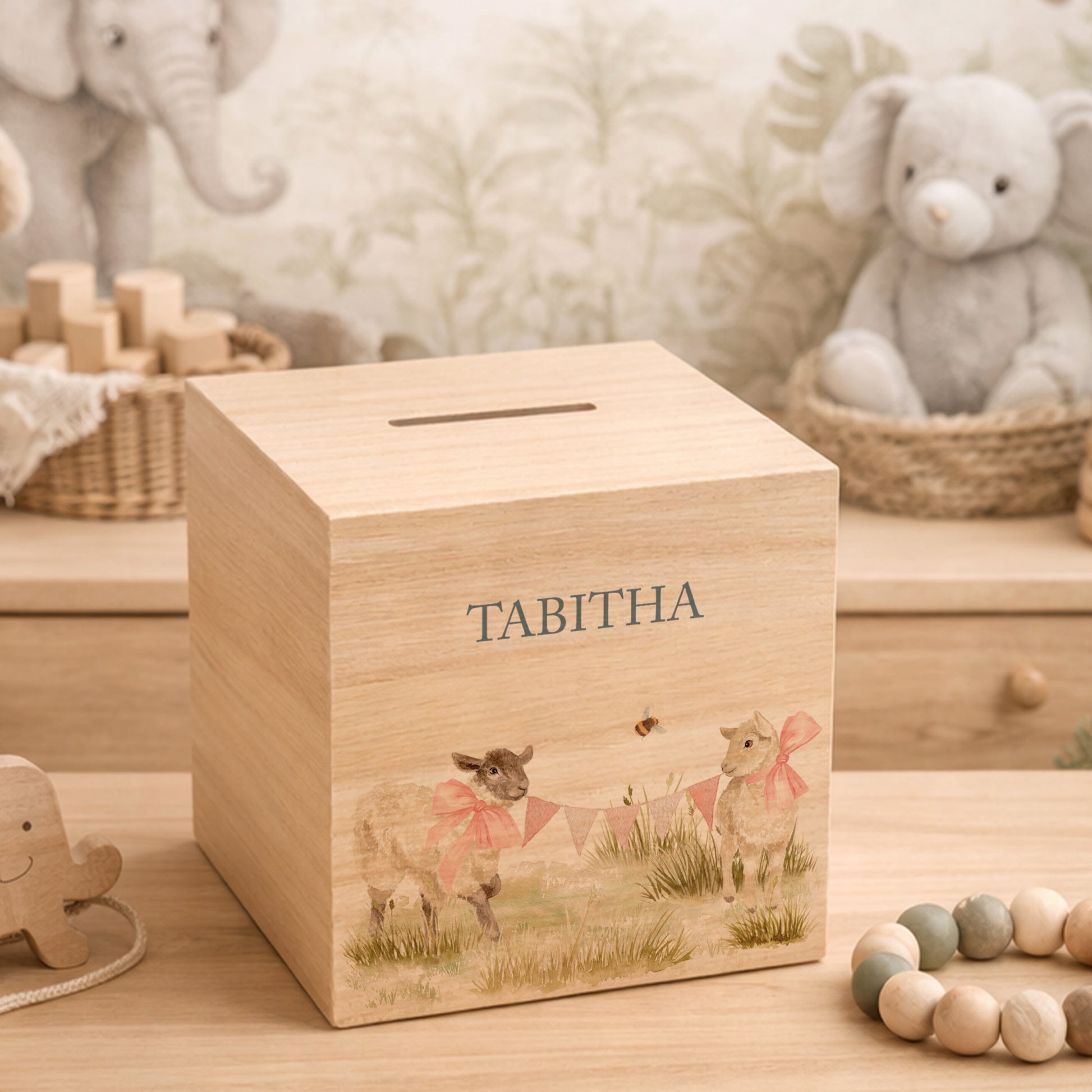 wooden handmade baby money box styled in a neutral childrens bedroom, cute lambs playing with bunting and bows around their necks